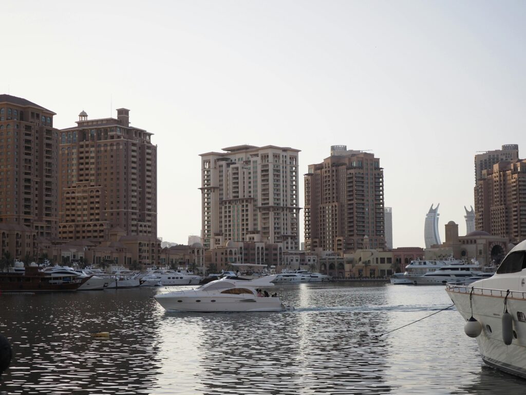 Stunning view of luxury yachts and modern architecture in Doha's marina at sunset.